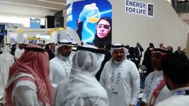 Attendees and exhibitors stand near a Abu Dhabi National Oil Company (ADNOC) poster during the Abu Dhabi International Petroleum Exhibition and Conference (ADIPEC) in Abu Dhabi, UAE, on October 31, 2022. (Reuters)