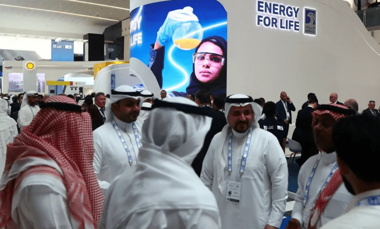 Attendees and exhibitors stand near a Abu Dhabi National Oil Company (ADNOC) poster during the Abu Dhabi International Petroleum Exhibition and Conference (ADIPEC) in Abu Dhabi, UAE, on October 31, 2022. (Reuters)