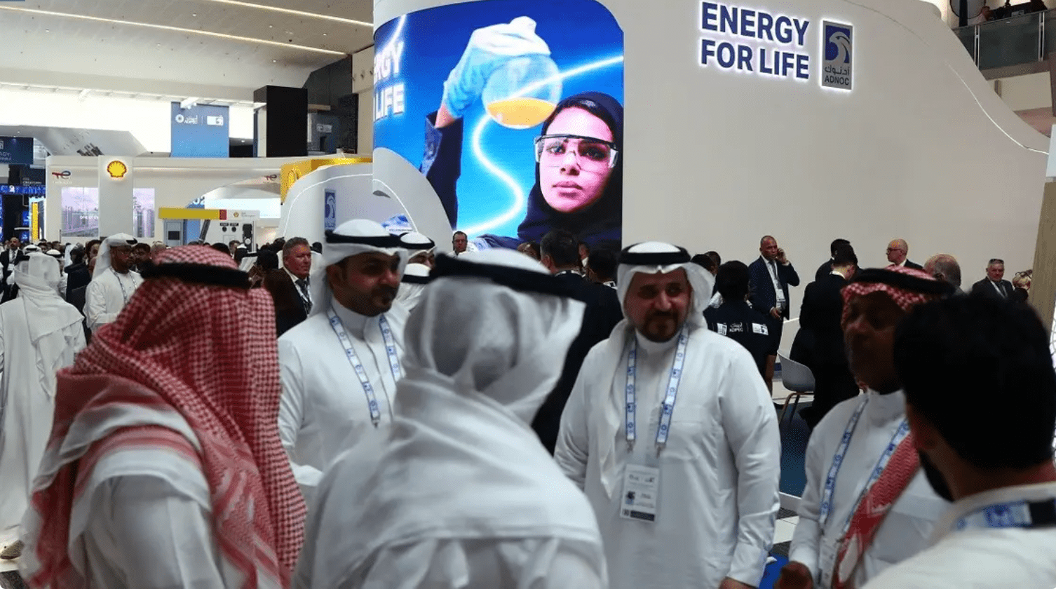 Attendees and exhibitors stand near a Abu Dhabi National Oil Company (ADNOC) poster during the Abu Dhabi International Petroleum Exhibition and Conference (ADIPEC) in Abu Dhabi, UAE, on October 31, 2022. (Reuters)